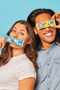 Woman on the left holding a coconut chocolate flavor snack bar, man on the right holding a lemon blueberry flavor snack bar